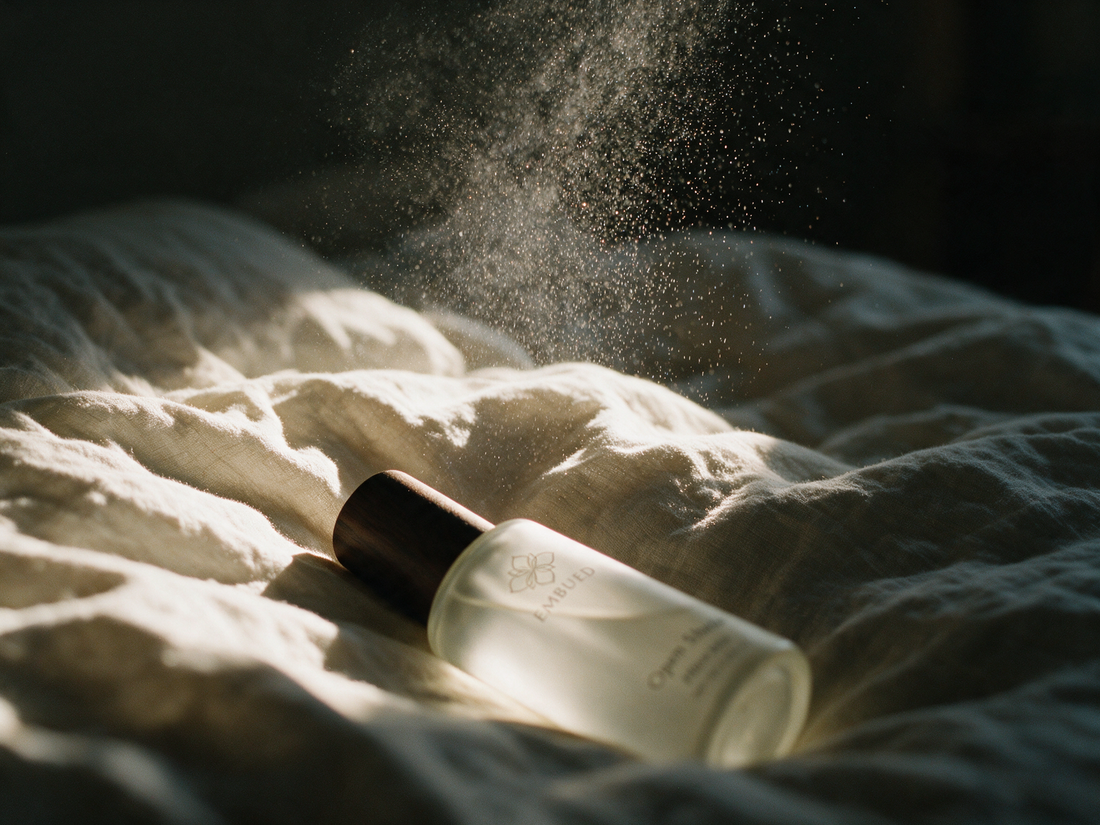 A fine mist settling onto linen bedding in low warm light, sprayed from an ethanol-free pillow mist
