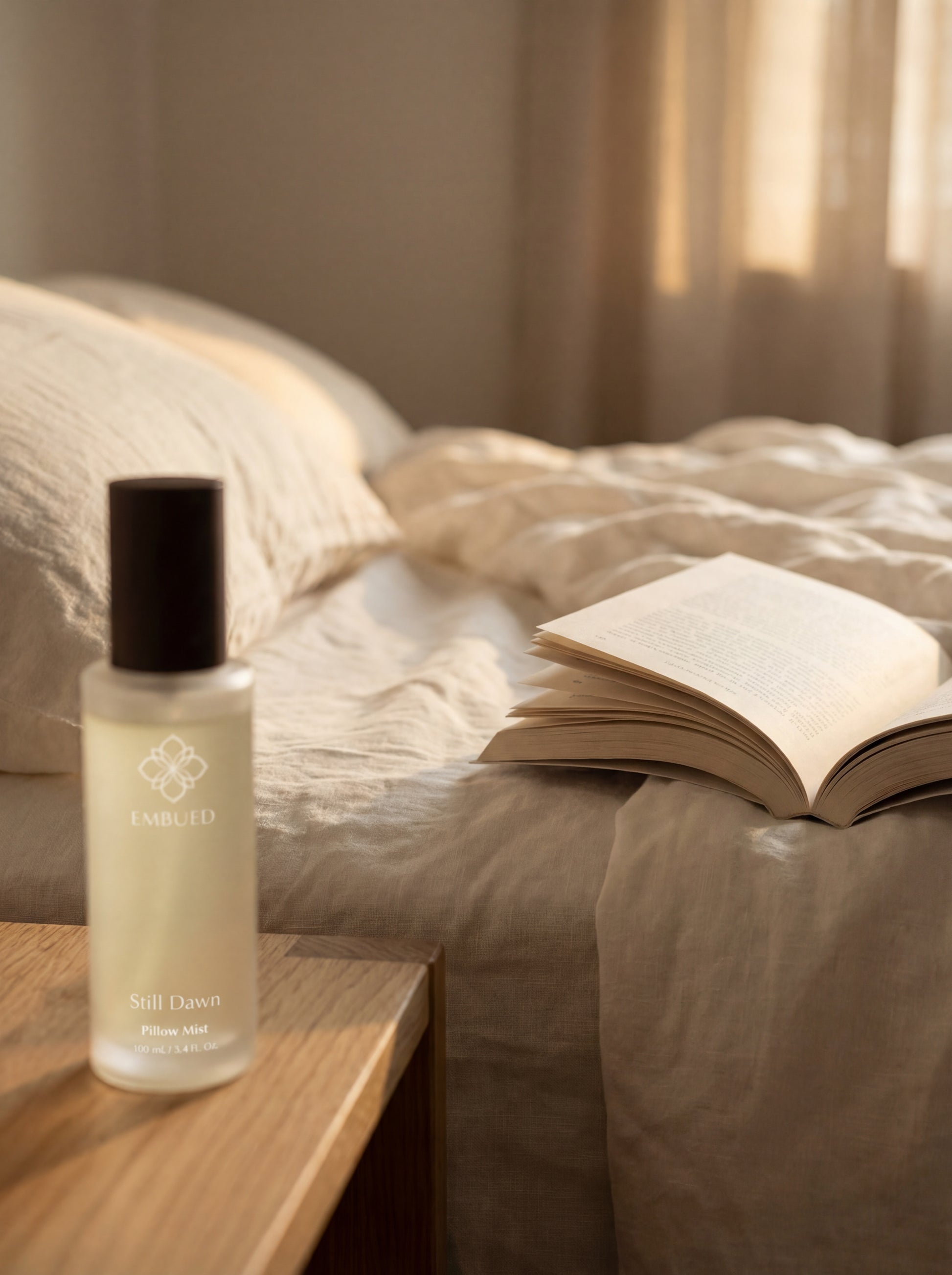 Skincare bottle on a wooden nightstand next to an open book on a bed